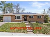 Charming brick home featuring solar panels, attached garage, manicured lawn, and inviting front porch at 4102 W Eastman Ave, Denver, CO 80236