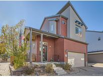 Inviting two-story home with red siding, well-kept landscaping, covered porch, and attached garage at 2514 Sweet Wind Ave, Castle Rock, CO 80109