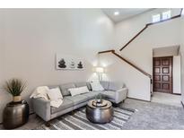 Bright living room featuring a comfortable gray sectional and stairs to the second floor at 206 S 22Nd Ave, Brighton, CO 80601