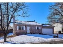 Brick ranch home with attached garage, nestled on a snow-covered lot at 19366 E Greenwood Pl, Aurora, CO 80013