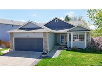Charming home featuring a two-car garage, stone accents and manicured lawn at 11560 River Run Cir, Commerce City, CO 80640