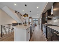 Modern kitchen features an island with seating, stainless steel appliances, and stylish pendant lighting at 2430 Ames St, Edgewater, CO 80214
