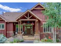 Charming home entrance featuring a covered porch, stone accents, and manicured landscaping at 31189 Manitoba Dr, Evergreen, CO 80439