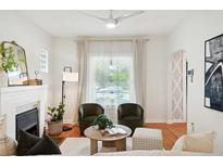Cozy living room features a fireplace, two armchairs, modern ceiling fan, and large window with sheer curtains at 3316 N Columbine St, Denver, CO 80205