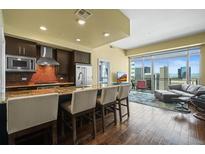 Modern kitchen with stainless steel appliances and granite countertops with seating, adjacent to open living area at 2001 Lincoln St # 2420, Denver, CO 80202