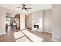 Bright living room with a modern fireplace, hardwood floors and a view to the kitchen with stainless steel appliances at 888 S Valentia St # 103, Denver, CO 80247