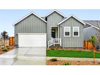 Charming gray home featuring a two-car garage, manicured lawn, and bright, modern design at 17125 W 92Nd Loop, Arvada, CO 80007