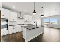 Modern kitchen features white cabinets, stainless steel appliances, a black island and dark hardwood floors at 17125 W 92Nd Loop, Arvada, CO 80007