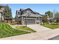 Charming home with a basketball hoop, stone accents, a well-manicured lawn, and a two-car garage at 9921 W Edenburg Pl, Littleton, CO 80127