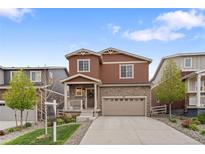 Charming two-story home with a stone and siding facade, a well-manicured lawn, and a two-car attached garage at 5311 Blue Lunar Ln, Castle Rock, CO 80104