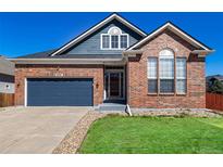 Charming brick and blue siding home with a well-maintained lawn and a blue garage door at 5999 E 114Th Ave, Thornton, CO 80233