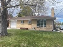 Charming brick home featuring a well-manicured lawn and attached garage, perfect for suburban living at 799 N Holly St, Denver, CO 80220