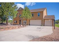 Charming two-story home with a three-car garage, beautiful trees, and a stone-accented entryway at 1822 Painter Dr, Monument, CO 80132