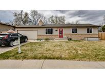 Charming single-story home featuring a red front door, attached garage, and well-maintained front yard at 11964 W 71St Pl, Arvada, CO 80004