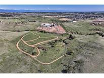 Expansive aerial view showcases the property's dirt track, riding area, and buildings against a backdrop of rolling hills at 1705 Outter Marker Rd, Castle Rock, CO 80108