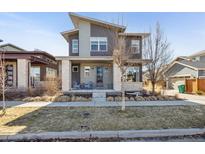 Beautiful modern home with a well-manicured front yard, covered entry and two rocking chairs at 10610 E 26Th Ave, Aurora, CO 80010