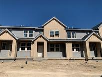 New construction townhome with gray and tan siding and a front entry door under a covered porch at 17143 W 91St Ln, Arvada, CO 80007