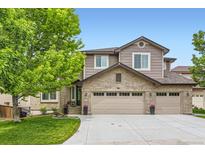 Charming home featuring a brick and siding exterior, three-car garage, manicured lawn, and mature tree at 989 Graland Pl, Highlands Ranch, CO 80126