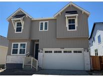 Charming two-story home with gray siding and a white garage door at 16488 W 92Nd Pl, Arvada, CO 80007