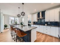 Modern kitchen featuring a large island with seating, stainless steel appliances, and a stylish backsplash at 2840 E 102Nd Pl, Thornton, CO 80229