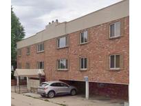 Three-story brick apartment building with covered parking and tan trim at 155 S Pennsylvania St # 209, Denver, CO 80209