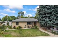 Charming brick home featuring a well-manicured lawn, mature trees, and a cozy front porch at 1217 Lincoln St, Longmont, CO 80501