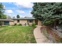 Charming single-story home featuring a well-manicured front yard, mature trees, and inviting curb appeal at 1217 Lincoln St, Longmont, CO 80501
