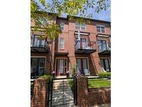 Brick townhome featuring balconies, a well-kept lawn, front gate, and potted plants at 4181 W 118Th Pl, Westminster, CO 80031