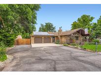 Charming stone home with a two-car garage, a well-maintained lawn, mature trees, and solar panels above the garage at 8644 S Brentwood St, Littleton, CO 80128