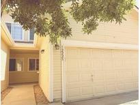 Light yellow home featuring a two-car garage with a tree providing shade at 12225 E 2Nd Dr, Aurora, CO 80011