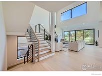 Bright living room featuring a cozy fireplace, modern furnishings and a grand staircase at 923 Saint Andrews Ln, Louisville, CO 80027