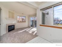 Bright living room features a corner fireplace, a large window, and sliding glass doors at 2850 Aurora Ave # 112, Boulder, CO 80303