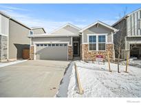 Charming home featuring a stone and gray exterior, two-car garage, and well-maintained front yard at 776 Griffith St, Lochbuie, CO 80603