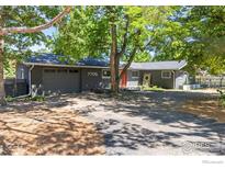 Gray house with an orange door, landscaping, and a driveway at 7705 Baseline Rd, Boulder, CO 80303
