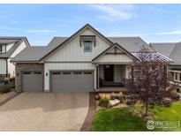 Charming home showcasing gray garage doors, white siding, and a beautifully landscaped front yard at 2920 Heron Lakes Pkwy, Berthoud, CO 80513