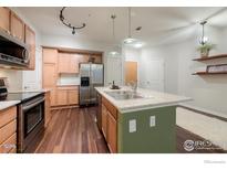 Open kitchen features stainless appliances, an island with sink and a breakfast bar at 13456 Via Varra # 114, Broomfield, CO 80020