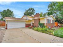 Charming home showcasing a brick facade, red shutters, a well-manicured lawn, and a two-car garage at 1638 Meeker Dr, Longmont, CO 80504