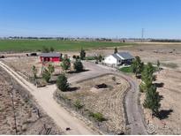 Stunning aerial view of the property featuring a charming home, red barn, and expansive land at 10691 County Road 23, Fort Lupton, CO 80621
