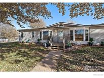Charming single-story home, features a welcoming porch, mature trees, and a well-maintained front yard at 10635 County Road 24, Fort Lupton, CO 80621