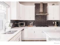 Well-lit kitchen with white cabinets, stainless steel appliances and dark backsplash at 20411 E 53Rd Ave, Denver, CO 80249