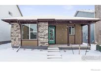 Charming craftsman style home with snow covered front yard and porch at 2763 Optimista Pl, Brighton, CO 80601