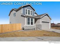 Two-story house with gray siding, stone accents, and a two-car garage at 791 Griffith St, Lochbuie, CO 80603