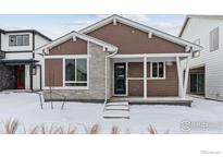Cute craftsman style home with a covered porch and snow-covered landscaping at 2779 Optimista Pl, Brighton, CO 80601