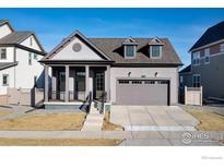 Charming gray home featuring a two-car garage and inviting front porch with steps at 1581 Poplar Dr, Erie, CO 80516