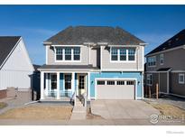 Charming two-story home with a well-manicured lawn, covered porch and welcoming blue and gray exterior at 1611 Poplar Dr, Erie, CO 80516