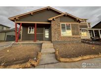 Newly constructed home with stone accents and a covered entryway at 2263 Serenidad St, Brighton, CO 80601