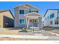 Charming two-story home features a gray brick and siding exterior, complemented by a well-maintained yard at 2283 Serenidad St, Brighton, CO 80601