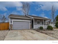 Charming single-story home with gray siding, a covered front porch, gray garage door and well-kept landscaping at 3557 Settler Ridge Dr, Mead, CO 80542