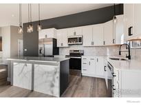 Modern kitchen with white cabinets, stainless steel appliances, and an island at 3557 Settler Ridge Dr, Mead, CO 80542