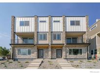 Modern two-unit townhome building with stone and white siding, balconies, and landscaping at 8500 W 62Nd Ave # H, Arvada, CO 80004